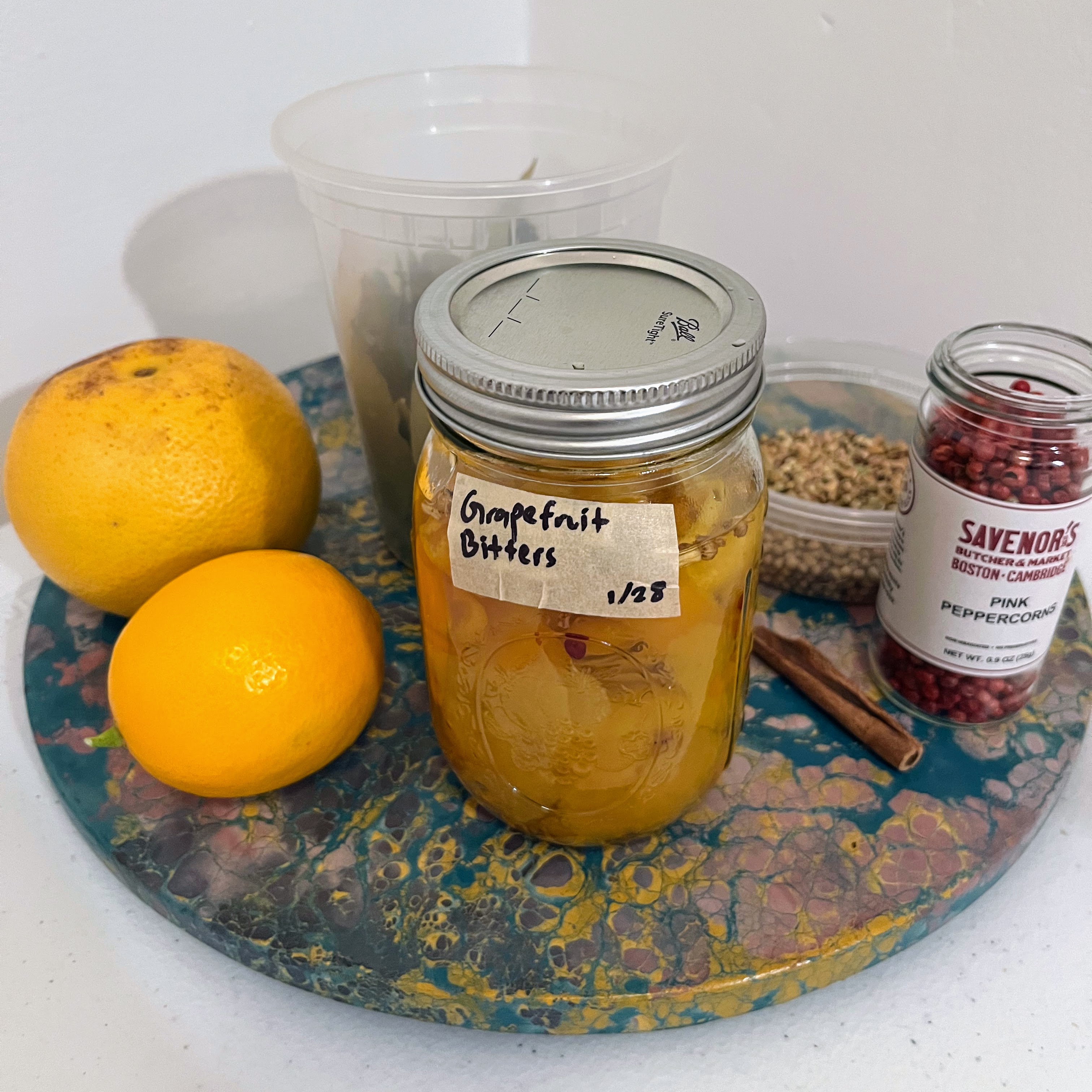 Ingredients for grapefruit bitters, including grapefruit, lemon, cinnamon, coriander seed, pink peppercorn, and bay leaf.